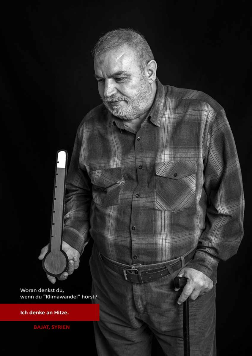 Ein älter Mann hält ein Thermometer aus Papier und der Hand. Er denkt an Hitze, wenn er Klimawandel hört.